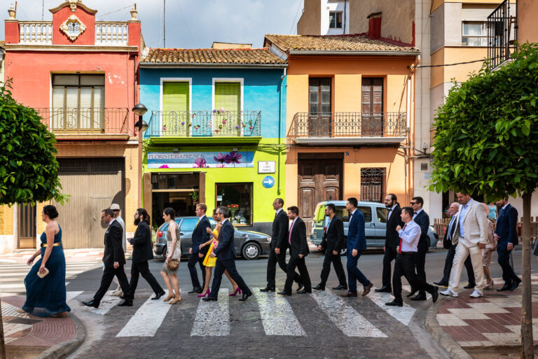 Fotografía de bodas documental: qué es | Adolf Boluda 3 Novio caminando hacia la iglesia acompañado de amigos y familia por las calles de Algemesí, fotografía de boda documental