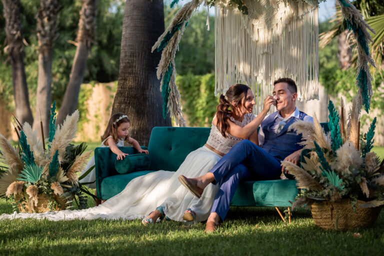 Fotógrafo de bodas natural y sin posados | Adolf Boluda 9 La novia seca una lágrima al novio durante la ceremonia mientras su hija juega junto a ellos, boda en Tu&Me Resort, Playa de Gandía (Valencia).