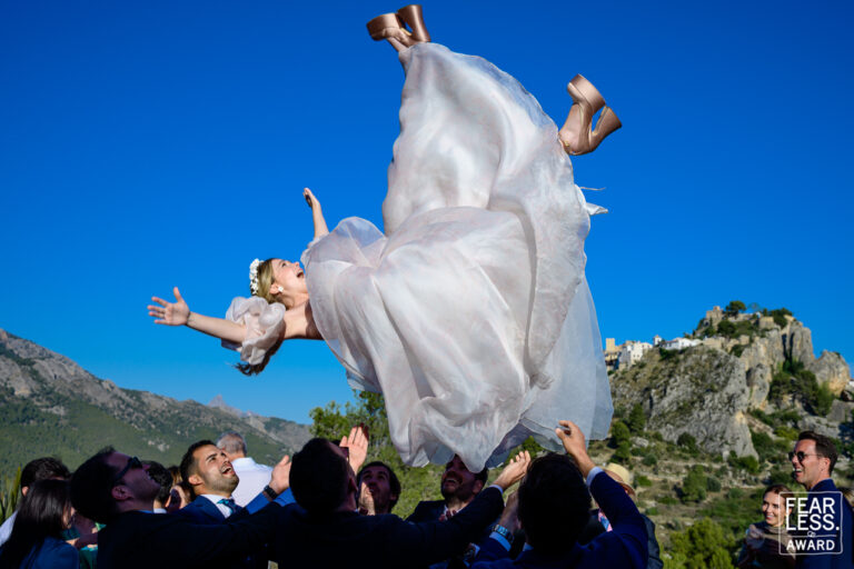 Fotógrafo de bodas natural y sin posados | Adolf Boluda 2 Manteo de la novia en la fiesta con el castillo de Guadalest al fondo, en Hotel Vivood, Benimantell (Alicante). Foto premiada con un Fearless Award.