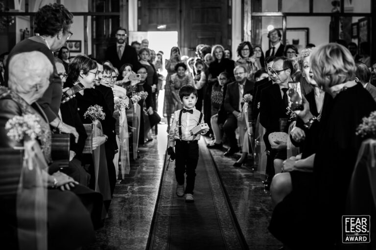 Fotógrafo de bodas natural y sin posados | Adolf Boluda 11 El sobrino del novio lleva los anillos al altar ante la mirada de todos los invitados, iglesia de Viver, Castellón. Foto premiada con un Fearless Award.